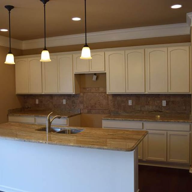 kitchen featuring white cabinetry, sink, pendant lighting, and light stone counters