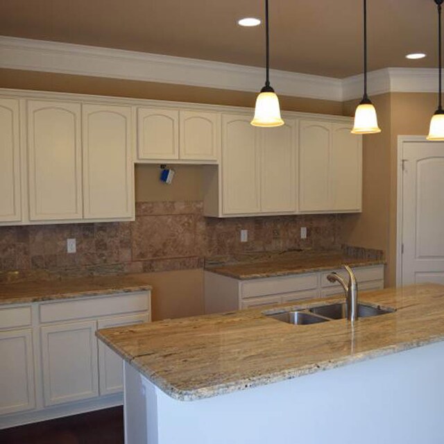 kitchen featuring light stone countertops, sink, pendant lighting, and white cabinets