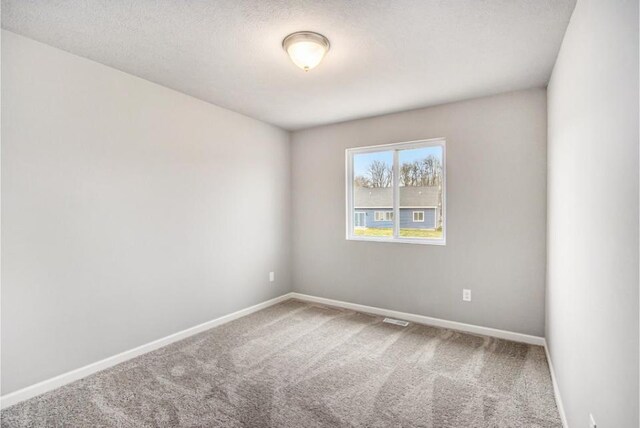 carpeted empty room with a textured ceiling