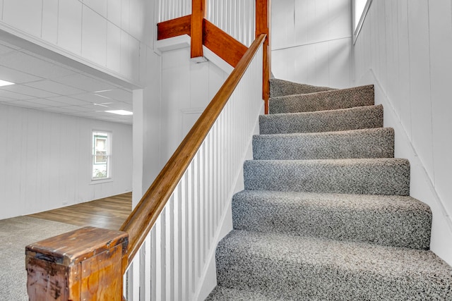 staircase with carpet and wooden walls