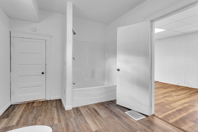 bathroom featuring wood walls, shower / tub combination, and hardwood / wood-style floors