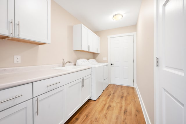 laundry area featuring light wood-type flooring, washing machine and dryer, cabinets, and sink