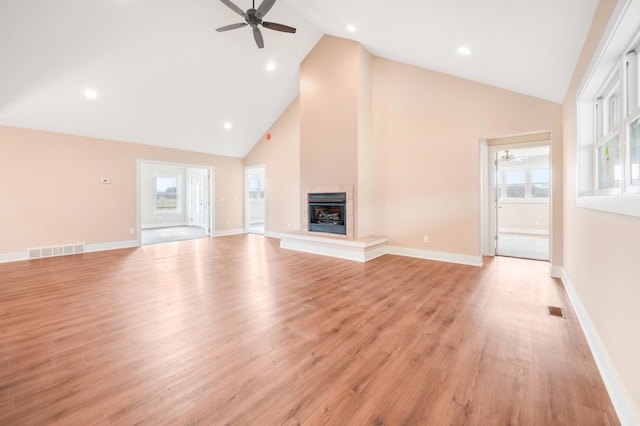 unfurnished living room featuring a wealth of natural light, ceiling fan, light wood-type flooring, and high vaulted ceiling