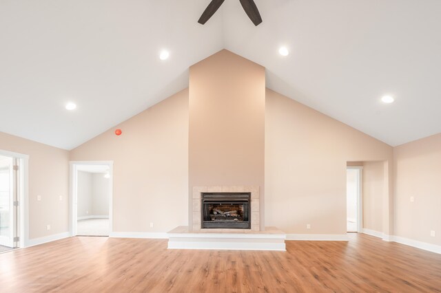 unfurnished living room featuring high vaulted ceiling, light hardwood / wood-style flooring, and a tile fireplace