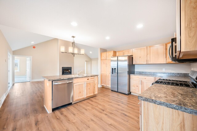 kitchen with stainless steel appliances, light brown cabinetry, and vaulted ceiling