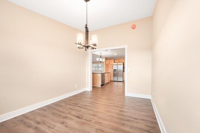 unfurnished dining area featuring a chandelier and light hardwood / wood-style floors