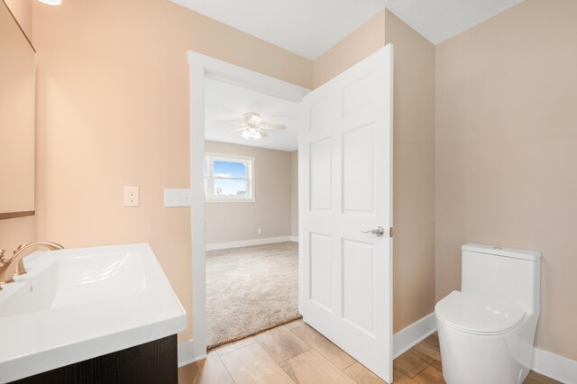 bathroom featuring toilet, vanity, and ceiling fan