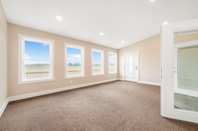 carpeted spare room with vaulted ceiling