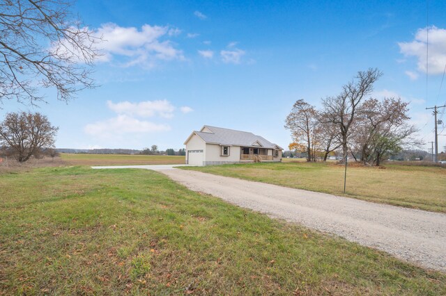 exterior space with a garage, a rural view, and a front lawn