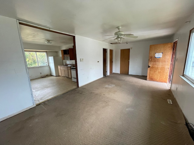 unfurnished living room with light colored carpet and ceiling fan