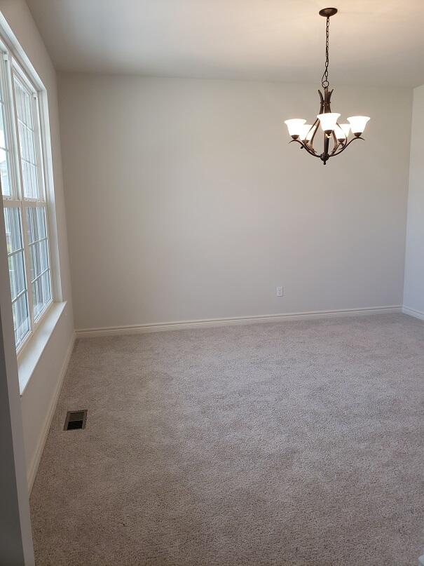 carpeted spare room with a notable chandelier