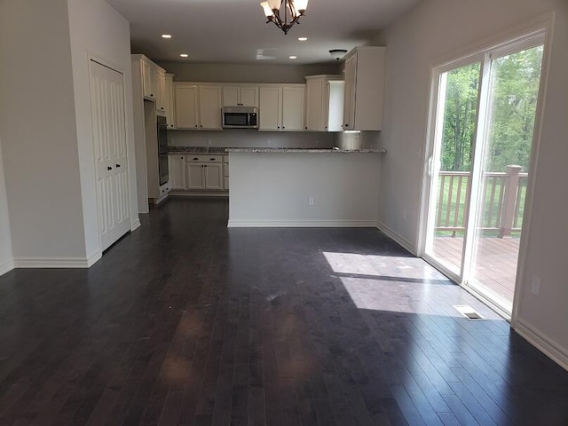 kitchen featuring white cabinetry, light stone countertops, dark hardwood / wood-style flooring, and kitchen peninsula