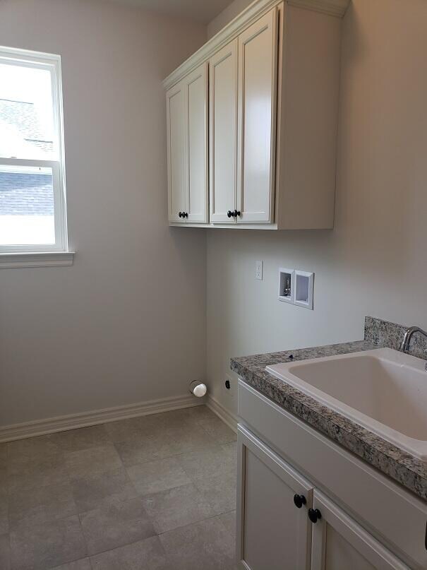 laundry area with sink, hookup for a washing machine, and cabinets