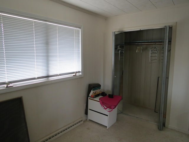 carpeted bedroom with a closet and a baseboard heating unit