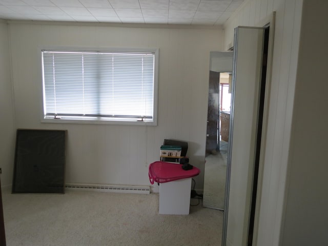 interior space with a wealth of natural light, a baseboard radiator, wooden walls, and light colored carpet