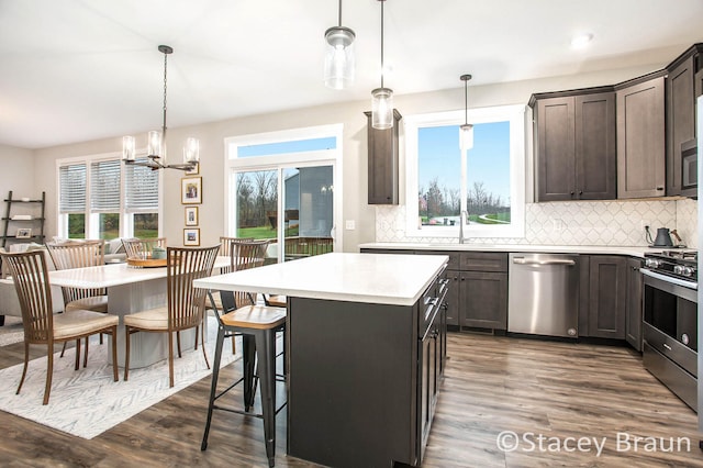 kitchen with dark hardwood / wood-style flooring, a center island, hanging light fixtures, and stainless steel appliances