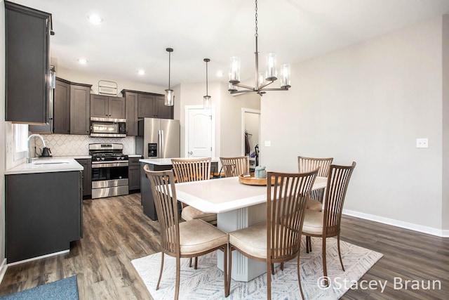 dining space with dark wood-type flooring, a chandelier, and sink