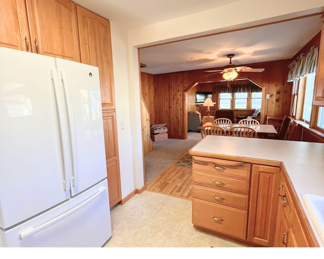 kitchen featuring ceiling fan, light tile patterned floors, white refrigerator, and wooden walls