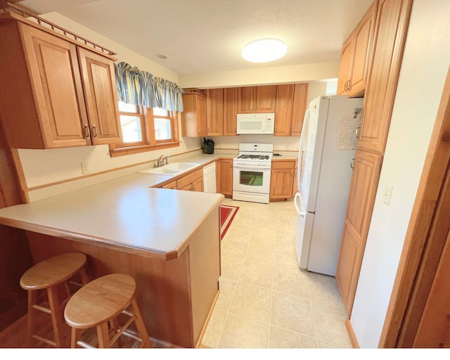 kitchen with sink, kitchen peninsula, white appliances, and a breakfast bar