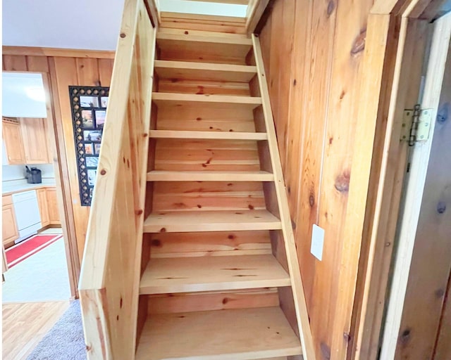 stairway featuring hardwood / wood-style flooring and wood walls