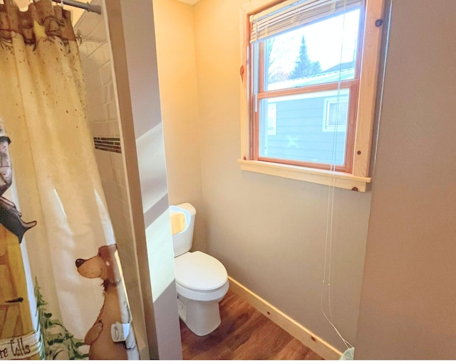 bathroom with toilet, hardwood / wood-style flooring, and a shower with curtain