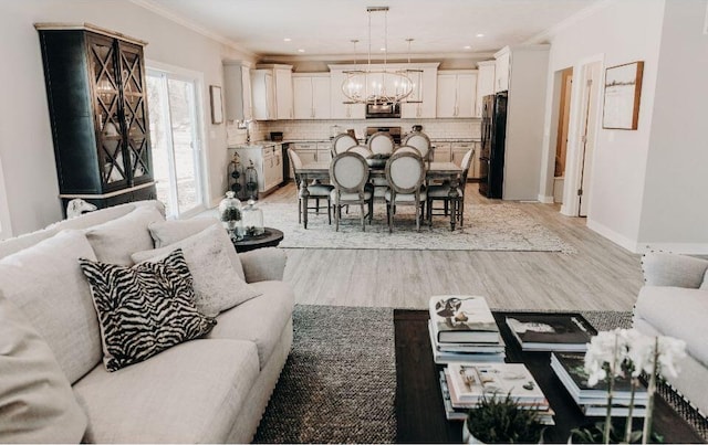 living room with a notable chandelier, ornamental molding, sink, and light wood-type flooring