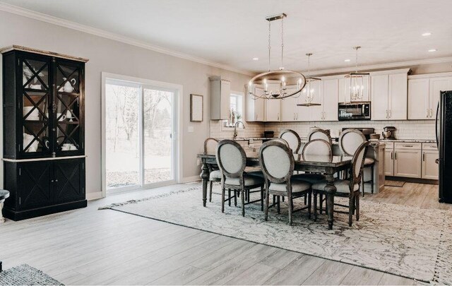 dining space with sink, ornamental molding, and light hardwood / wood-style flooring