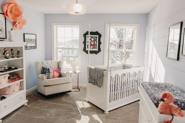 bedroom featuring carpet flooring, wooden walls, and a crib