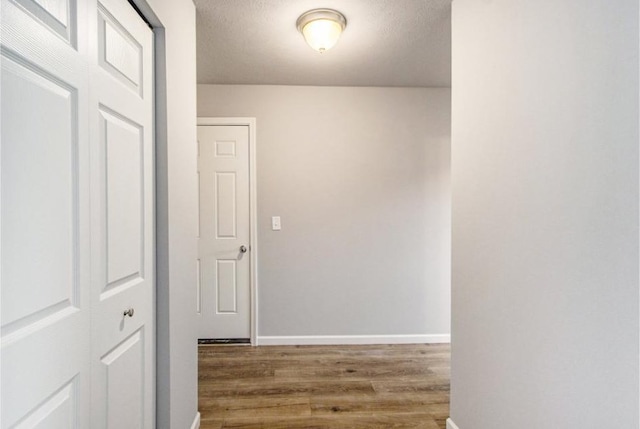 hall with hardwood / wood-style floors and a textured ceiling