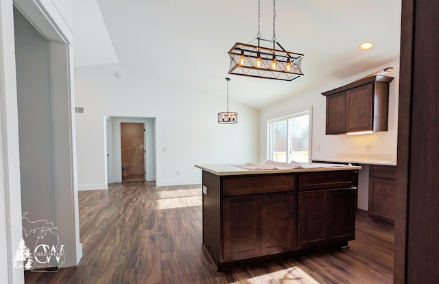 kitchen featuring dark wood-type flooring, a center island, dark brown cabinetry, decorative light fixtures, and vaulted ceiling