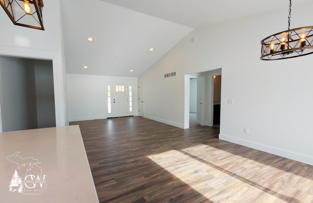 unfurnished living room with an inviting chandelier, dark hardwood / wood-style flooring, and high vaulted ceiling