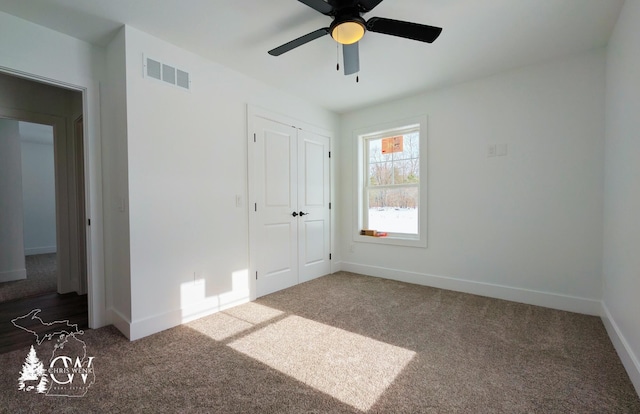 unfurnished bedroom with dark carpet, a closet, and ceiling fan