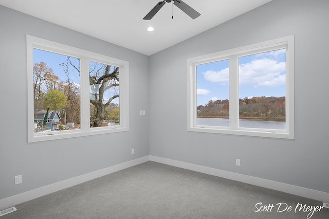 carpeted spare room featuring a water view, a healthy amount of sunlight, ceiling fan, and vaulted ceiling