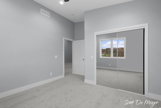 unfurnished bedroom with light carpet and a closet