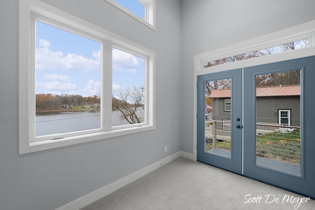 doorway to outside with french doors, light colored carpet, and a water view