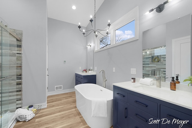 bathroom with an inviting chandelier, vanity, wood-type flooring, and separate shower and tub