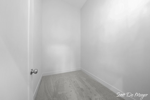 carpeted empty room featuring lofted ceiling