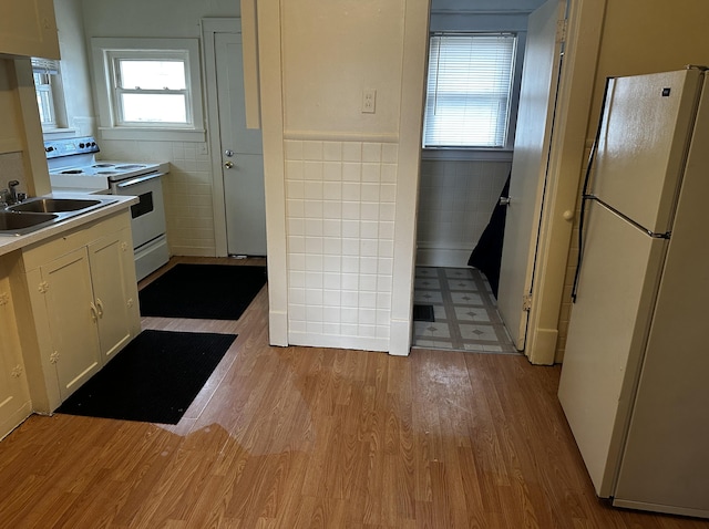 kitchen featuring tile walls, sink, light hardwood / wood-style floors, and white appliances