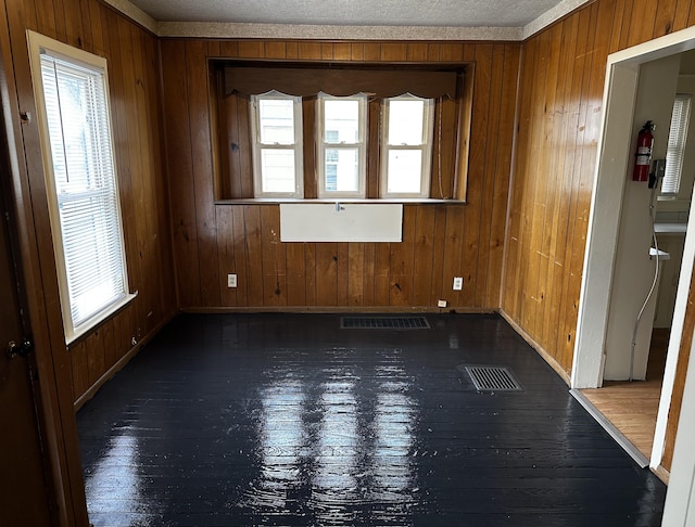 spare room featuring wooden walls and dark wood-type flooring