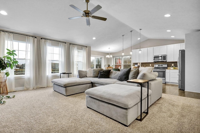 living room with light hardwood / wood-style flooring, lofted ceiling, and ceiling fan with notable chandelier