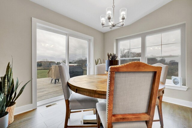 dining space with wood-type flooring, a chandelier, and vaulted ceiling