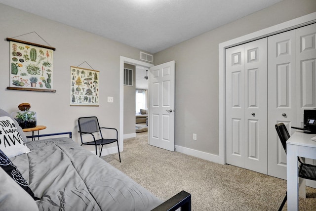 bedroom with a closet, a textured ceiling, and light colored carpet