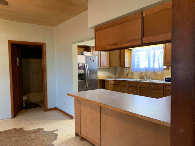 kitchen featuring sink, kitchen peninsula, and stainless steel refrigerator with ice dispenser