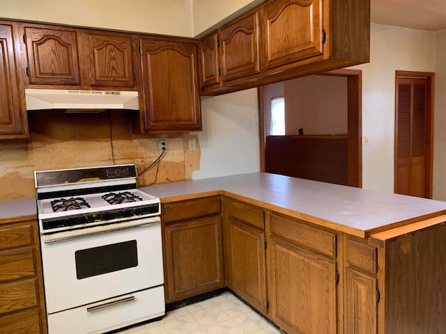 kitchen featuring white gas range oven, backsplash, and kitchen peninsula