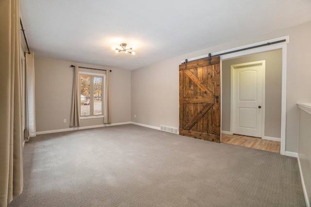 carpeted empty room with a barn door