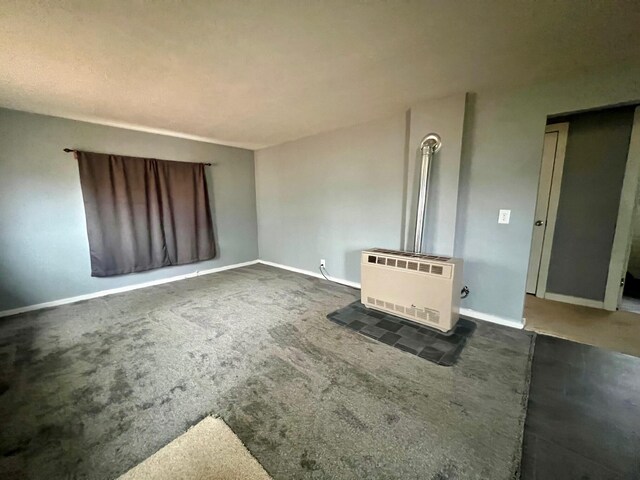 unfurnished living room featuring dark colored carpet and heating unit