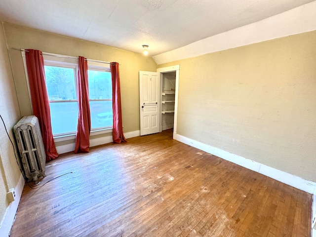 spare room featuring radiator and hardwood / wood-style flooring