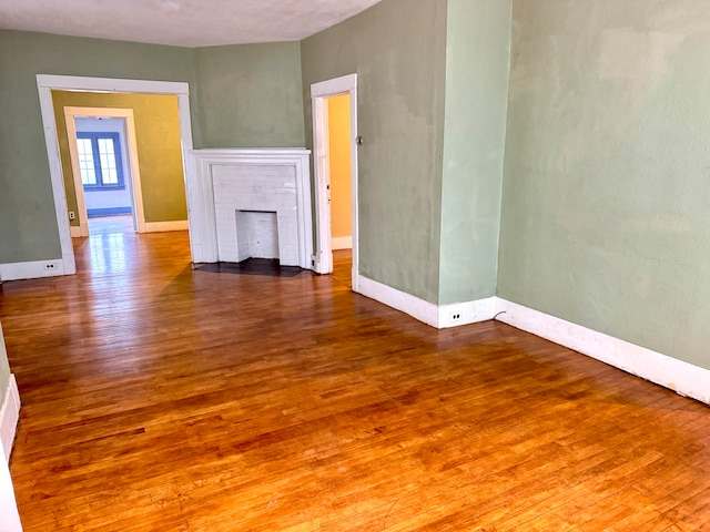 unfurnished living room with a tiled fireplace and wood-type flooring