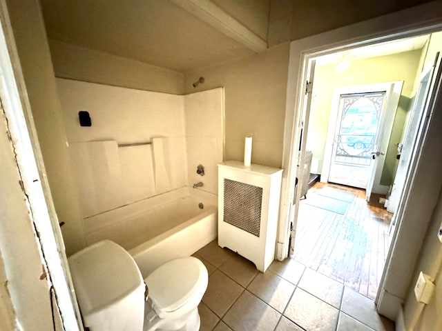 bathroom with toilet, a tub to relax in, and tile patterned flooring