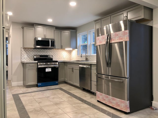 kitchen featuring appliances with stainless steel finishes, sink, decorative backsplash, and gray cabinets